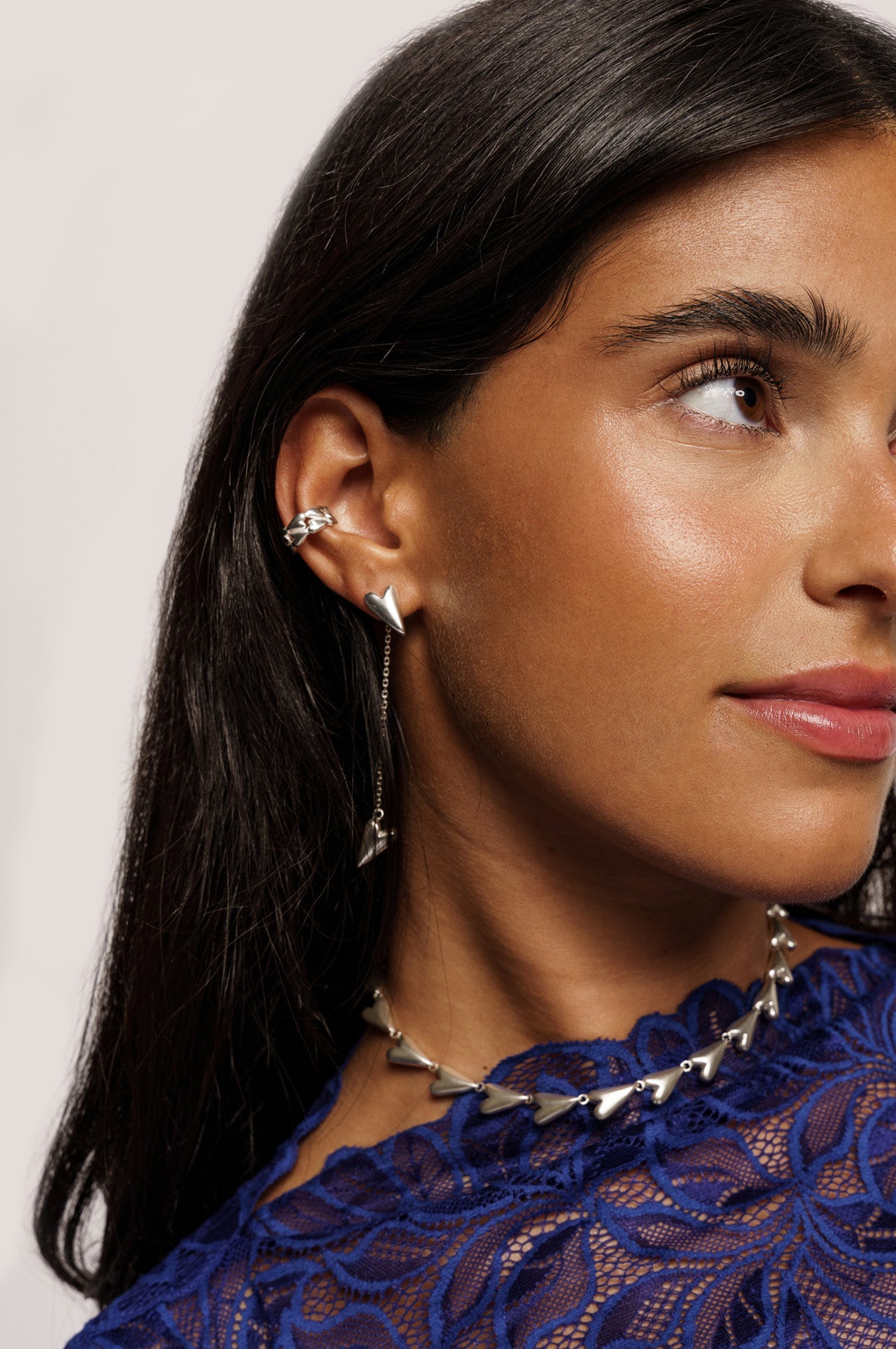 An earcuff with tiny hearts, a long pair of earrings with chain and a heart at the bottom and also a chain necklace only made with hearts